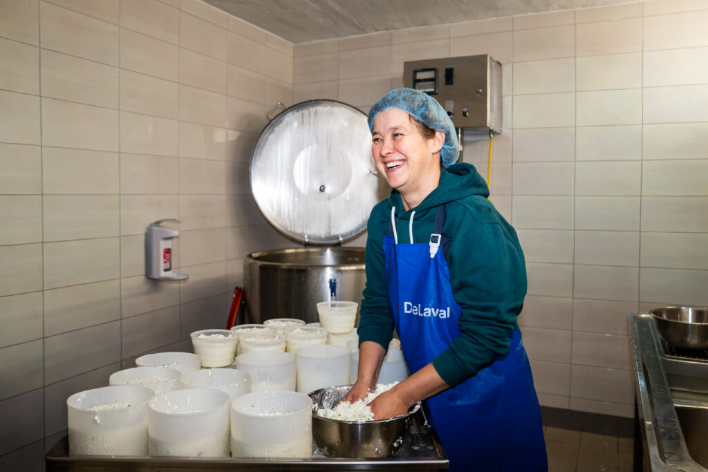 Das Foto zeigt Bäuerin Conny beim Kneten von körnigem Frischkäse.