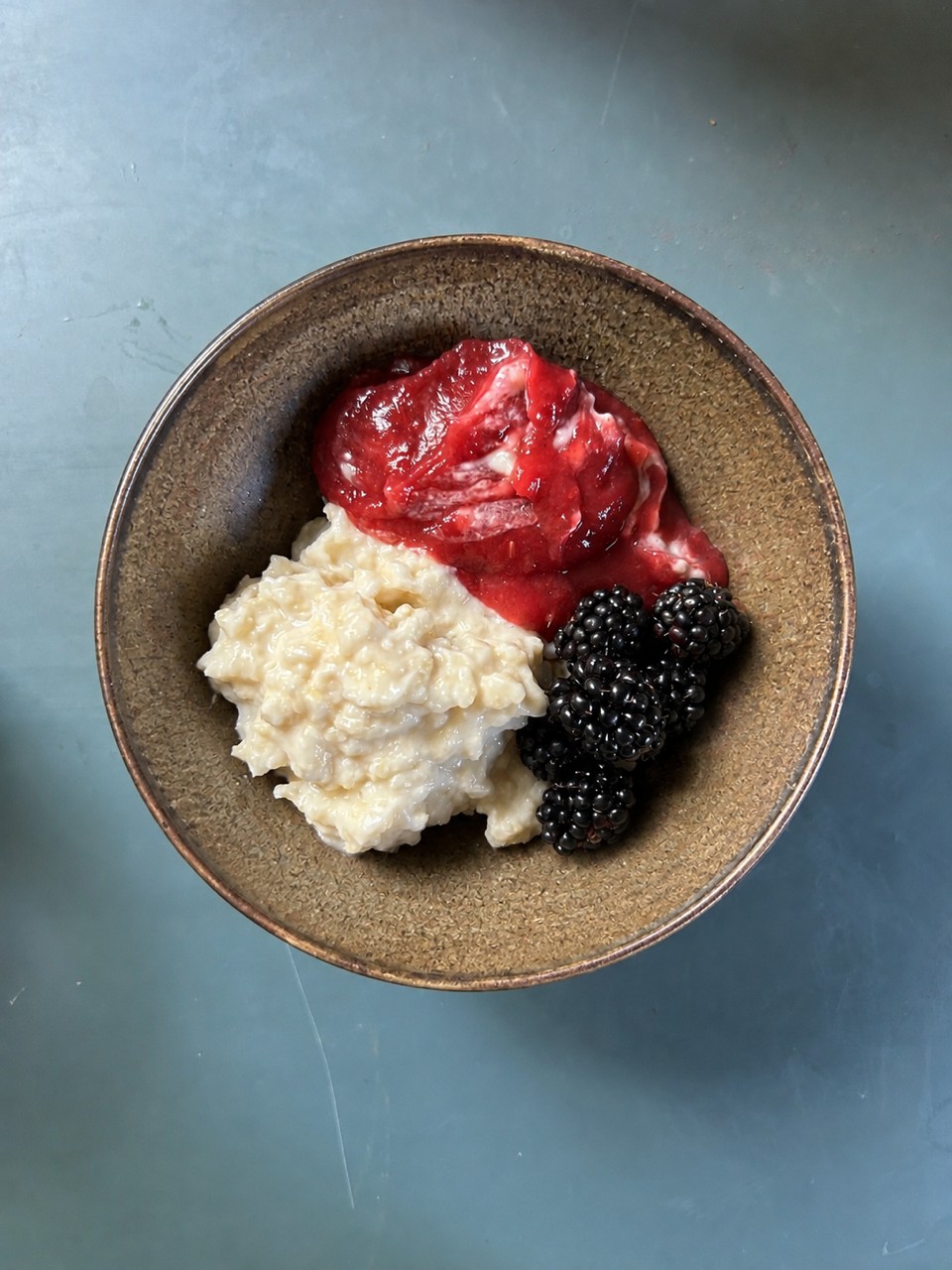 Das Foto zeigt eine Schale mit Hirsebrei, Heidelbeeren und Erdbeermarmelade